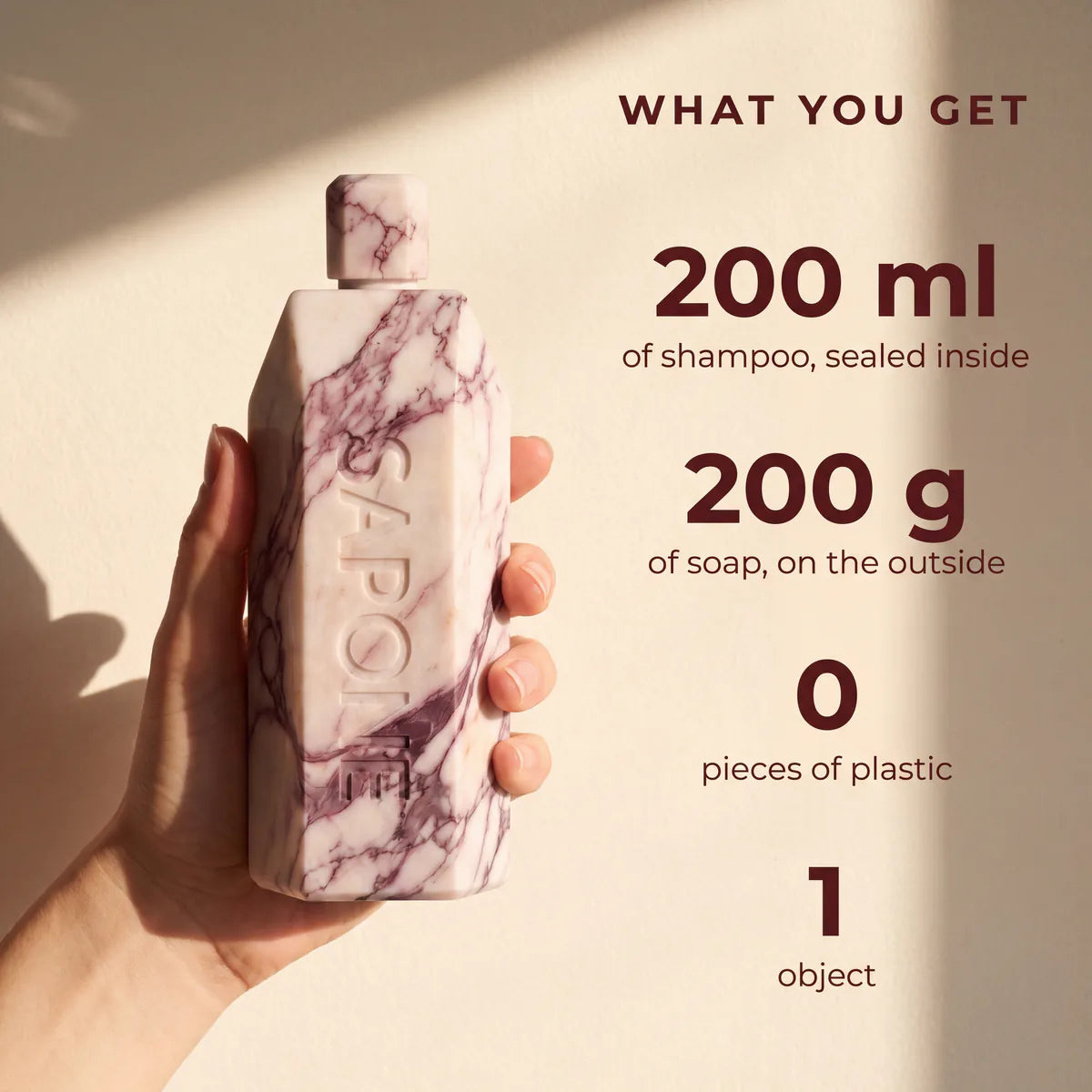 A hand holding a Sapone bottle, showing what you get: 200 ml of shampoo sealed inside, 200 g of soap on the outside, zero pieces of plastic, all in one object.
